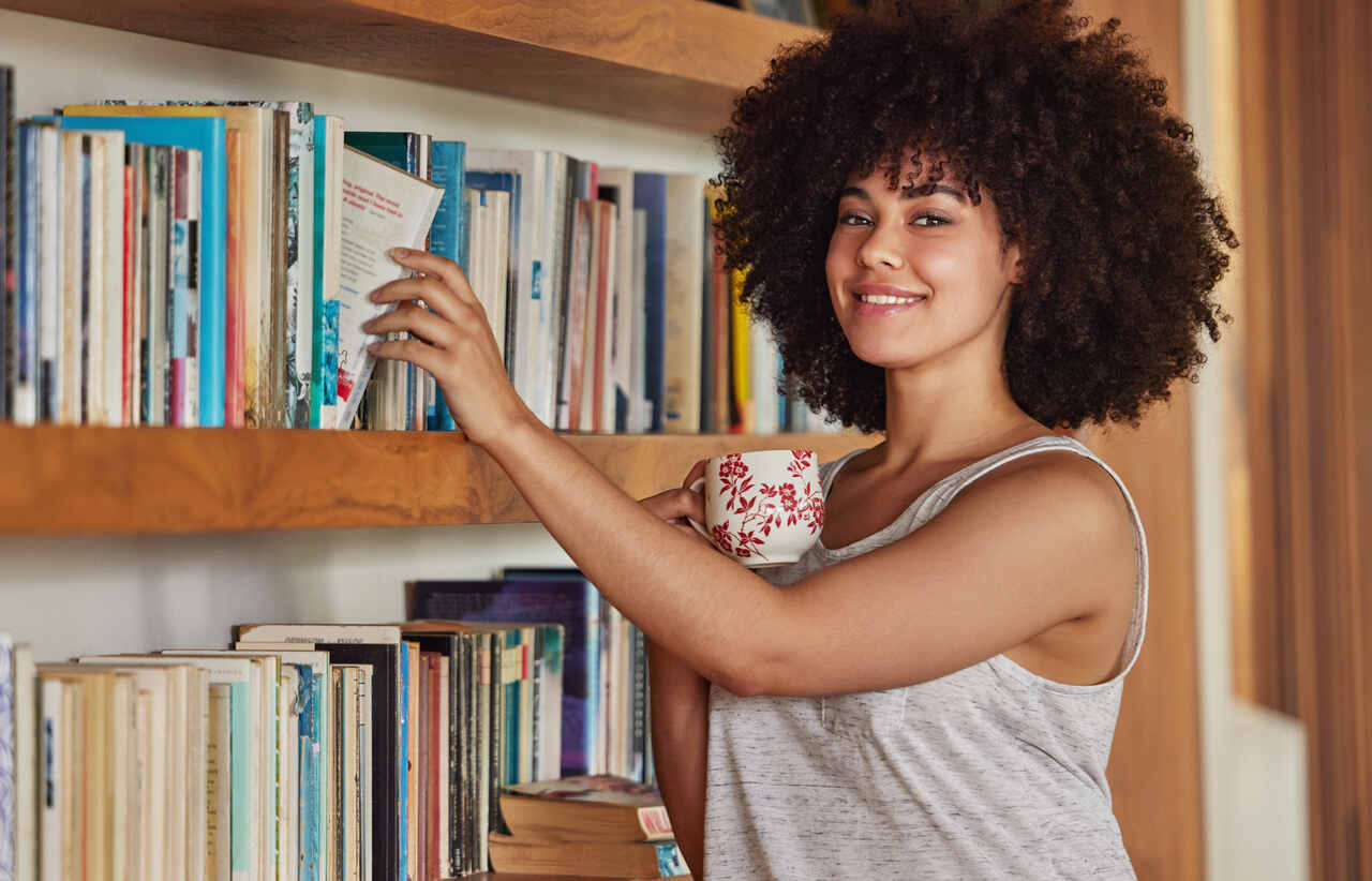 woman-portrait-bookshelf-book-choice-with-coffee-home-story-fiction-education-relax-with-drink-female-person-apartment-house-library-books-reading-hot-beverage_Easy-Resize.com_ Notícias